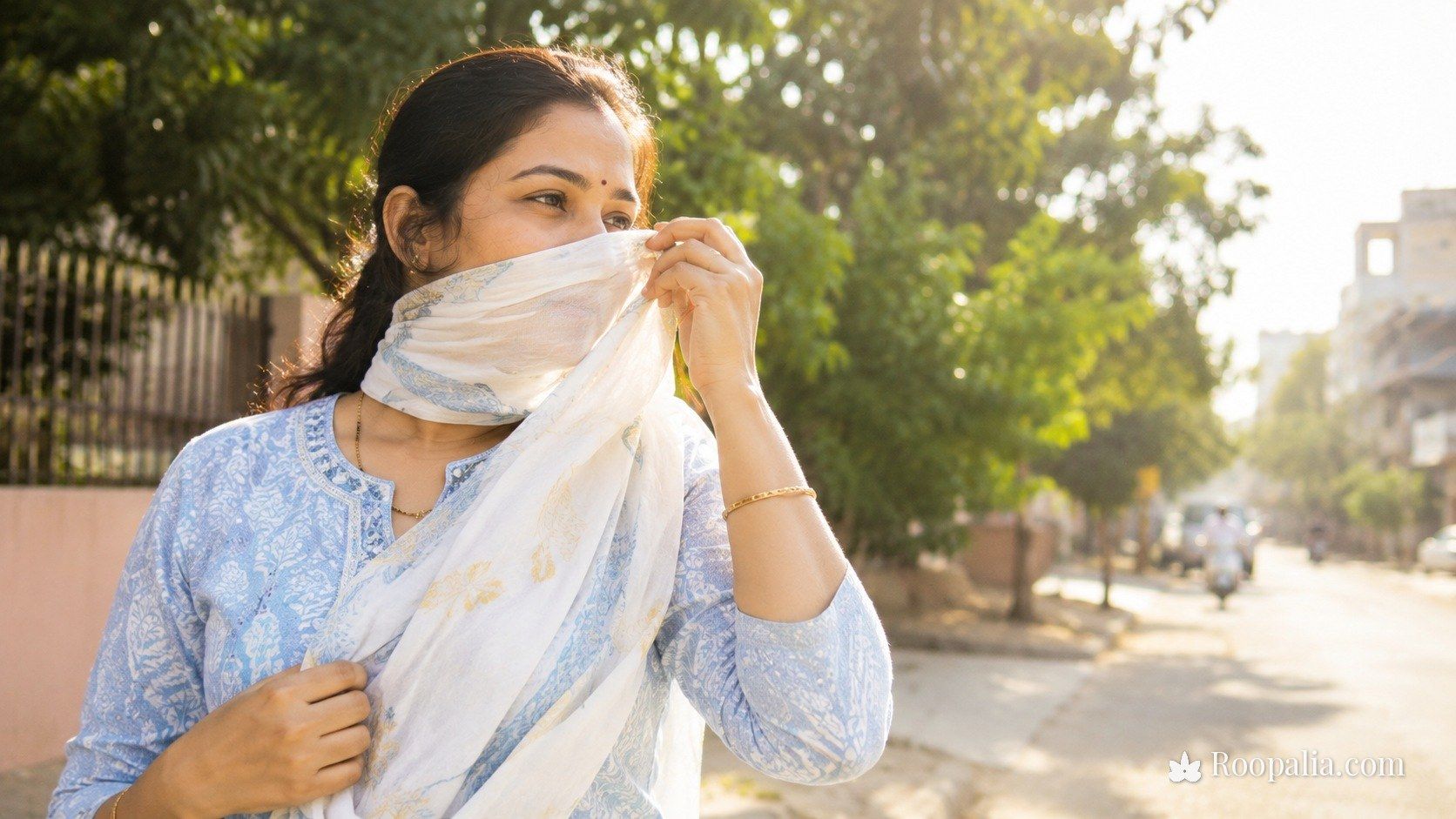 धूप से त्वचा का बचाव — दुपट्टे से चेहरा ढँककर धूप में चलती भारतीय महिला